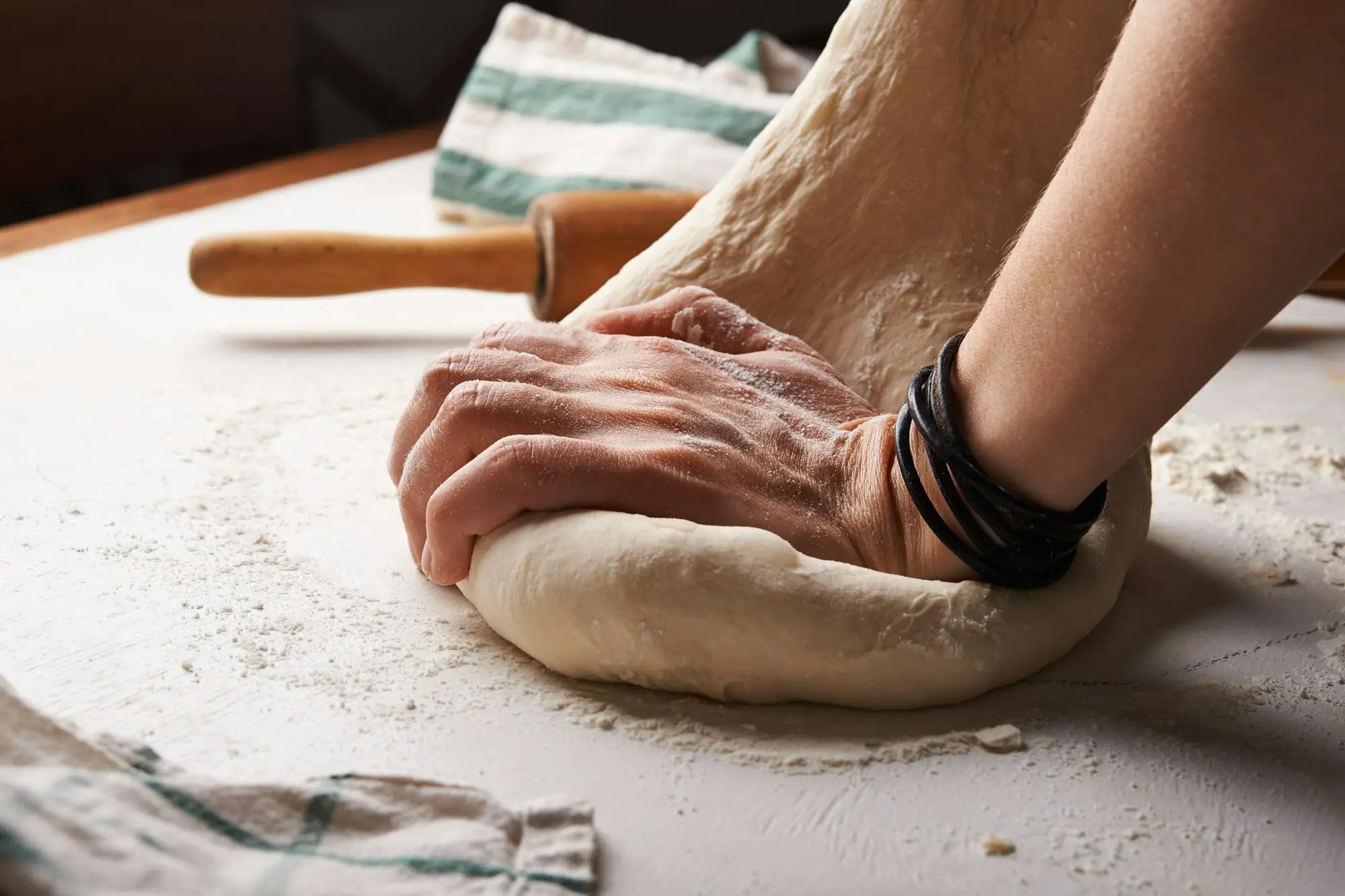 Baker kneading dough on a floured bench before opening