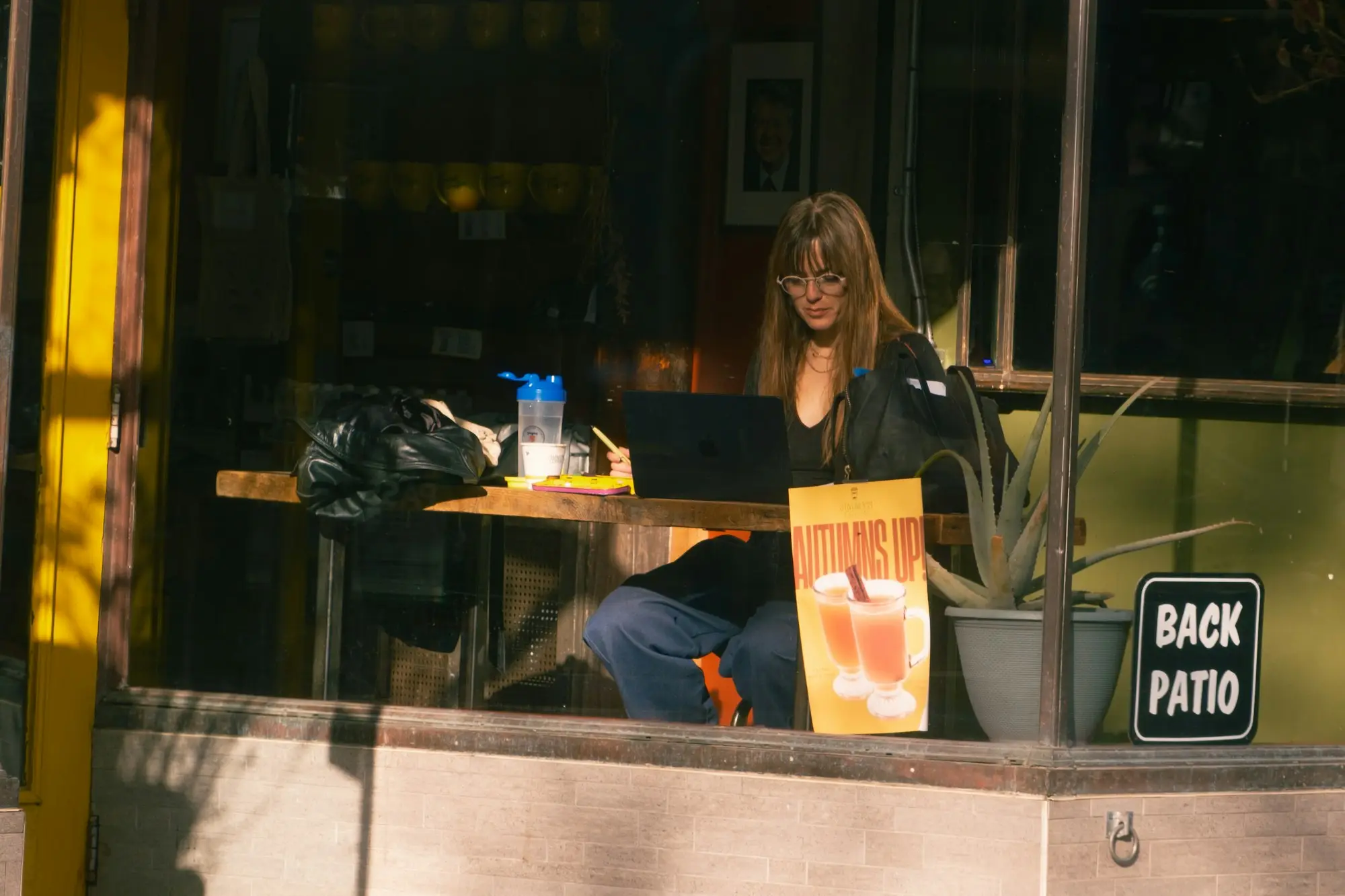 Cafe owner working on a laptop at a window table in the morning
