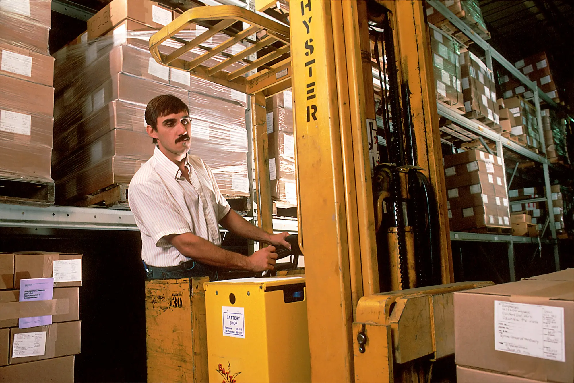 Warehouse manager checking an invoice beside a forklift